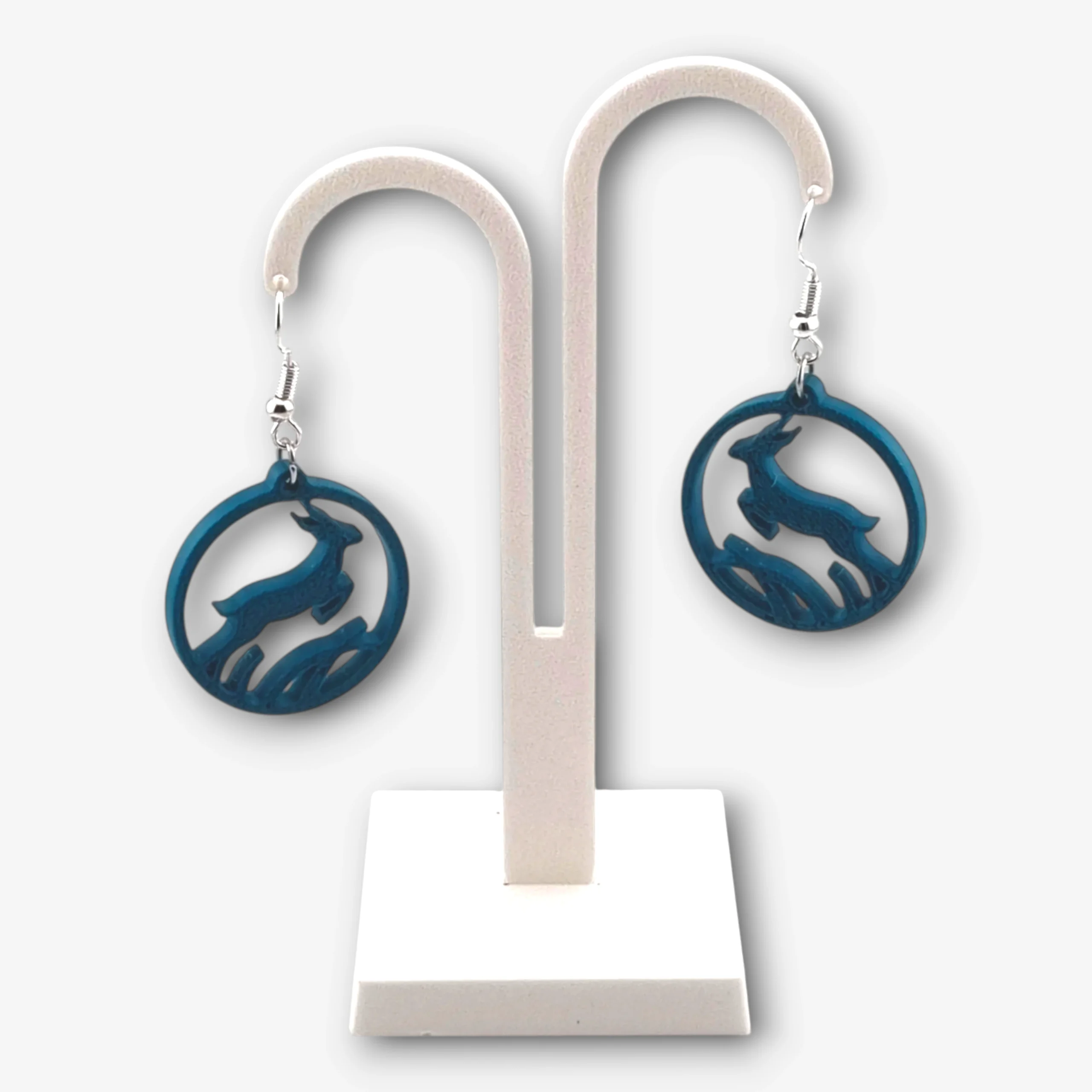 A pair of dark green Springbok Rugby earrings on a stand